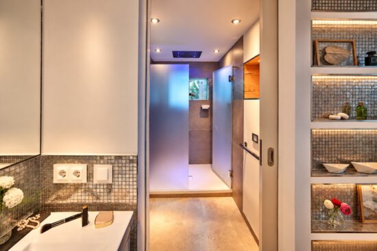 Alt Text Elegant bathroom in the Royal Three-Bedroom Penthouse Residence Heidelberg with walk-in shower, mosaic tiles and atmospheric lighting
