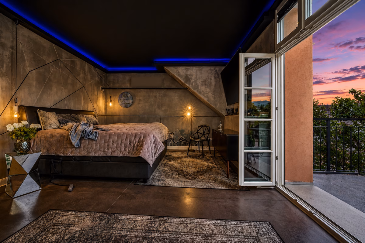 Executive Design Loft Heidelberg bedroom with double bed, open balcony doors and evening view