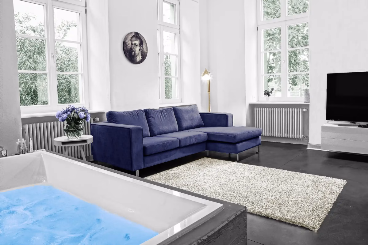 Living room with blue sofa and in-room whirlpool in Heidelberg loft
