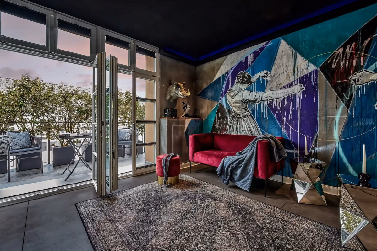 Living room with artistic wall design and access to balcony in the Superior Loft Heidelberg.