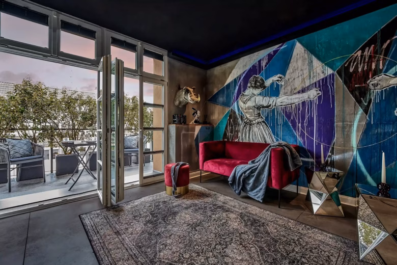 Living room with artistic wall design and access to balcony in the Superior Loft Heidelberg.
