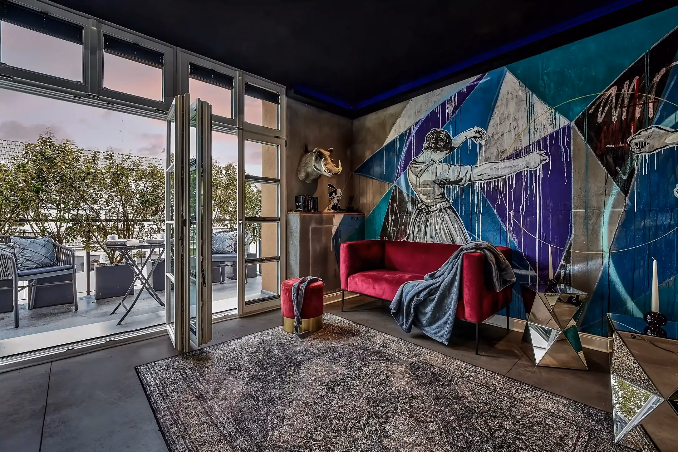 Living room with artistic wall design and access to balcony in the Superior Loft Heidelberg.