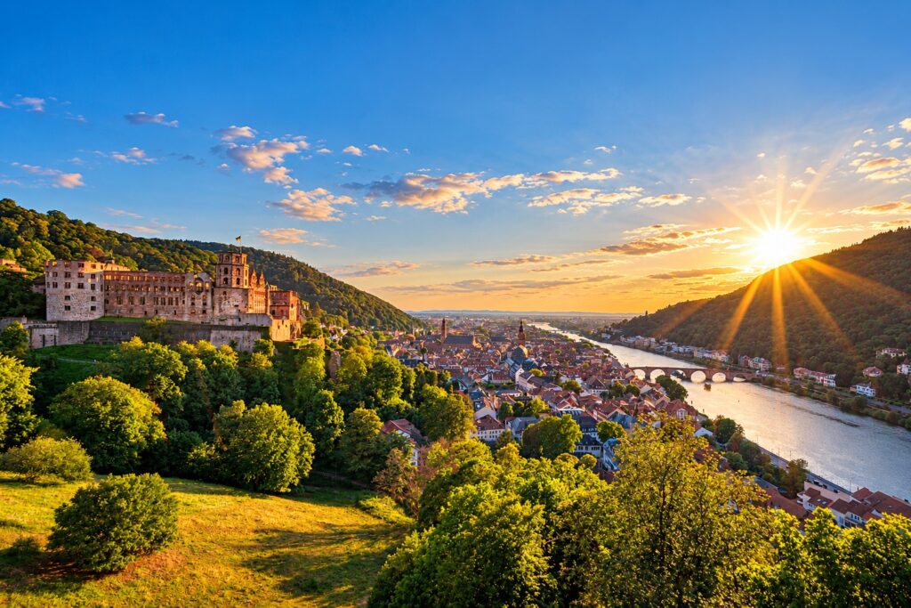 Panoramic view of Heidelberg Castle, the historic Old Town and the Neckar River in warm evening light.