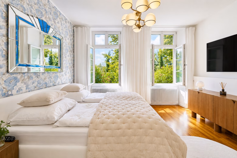 Bright bedroom in the Imperial Two-Bedroom Suite Heidelberg with double bed, large windows and garden view