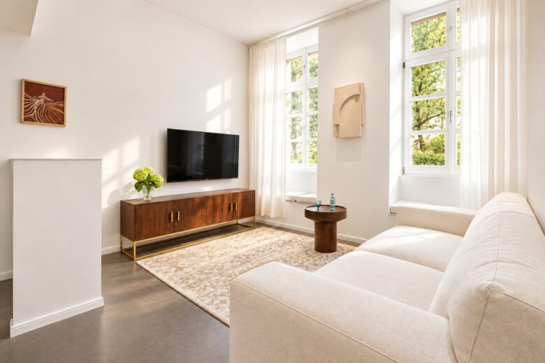 Bright private living area of the Business One-Bedroom Residence Heidelberg with sofa, TV and natural daylight