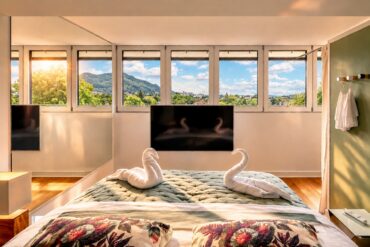 Bright bedroom in the Royal Three-Bedroom Penthouse Residence Heidelberg with panoramic windows, view and towel swans