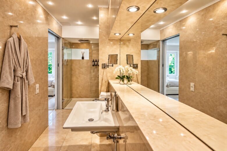 Elegant private bathroom in the Signature Two-Bedroom Suite Heidelberg with walk-in shower, warm stone surfaces and a prepared bathrobe