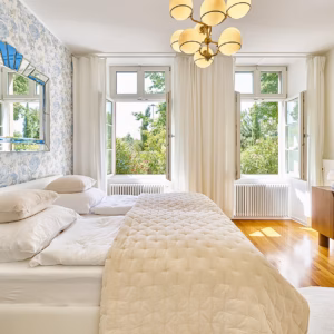 Bright bedroom in the Imperial Suite Heidelberg with large windows, floral wallpaper, and a comfortable king-size bed – ideal for long stays.