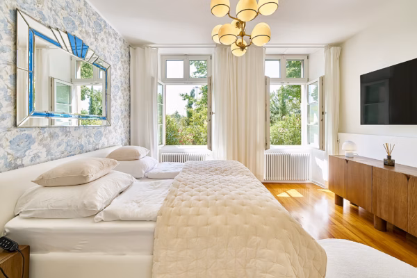 Bright bedroom in the Imperial Suite Heidelberg with large windows, floral wallpaper, and a comfortable king-size bed – ideal for long stays.