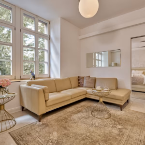 Bright living area with large windows, leather sofa, and stylish décor in the Grand Superior Suite Heidelberg – designed for long-term luxury stays.