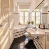 Bright private bathroom in the Family Apartment Heidelberg with bathtub, white pleated blinds and soft natural light.